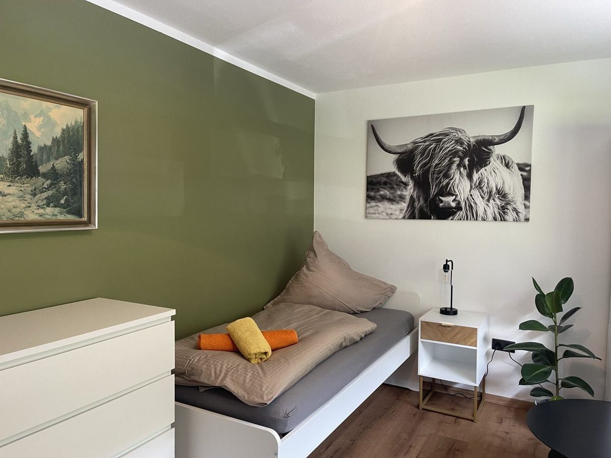 Schlafzimmer mit Einzelbett und grüner Wand in der Ferienwohnung im Montafon
